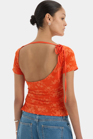 Bright orange fitted top with short sleeves and a floral pattern.