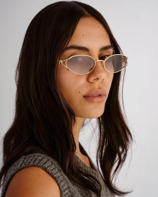 Gold oval frame sunglasses featuring slim split temples and gradient grey lenses.